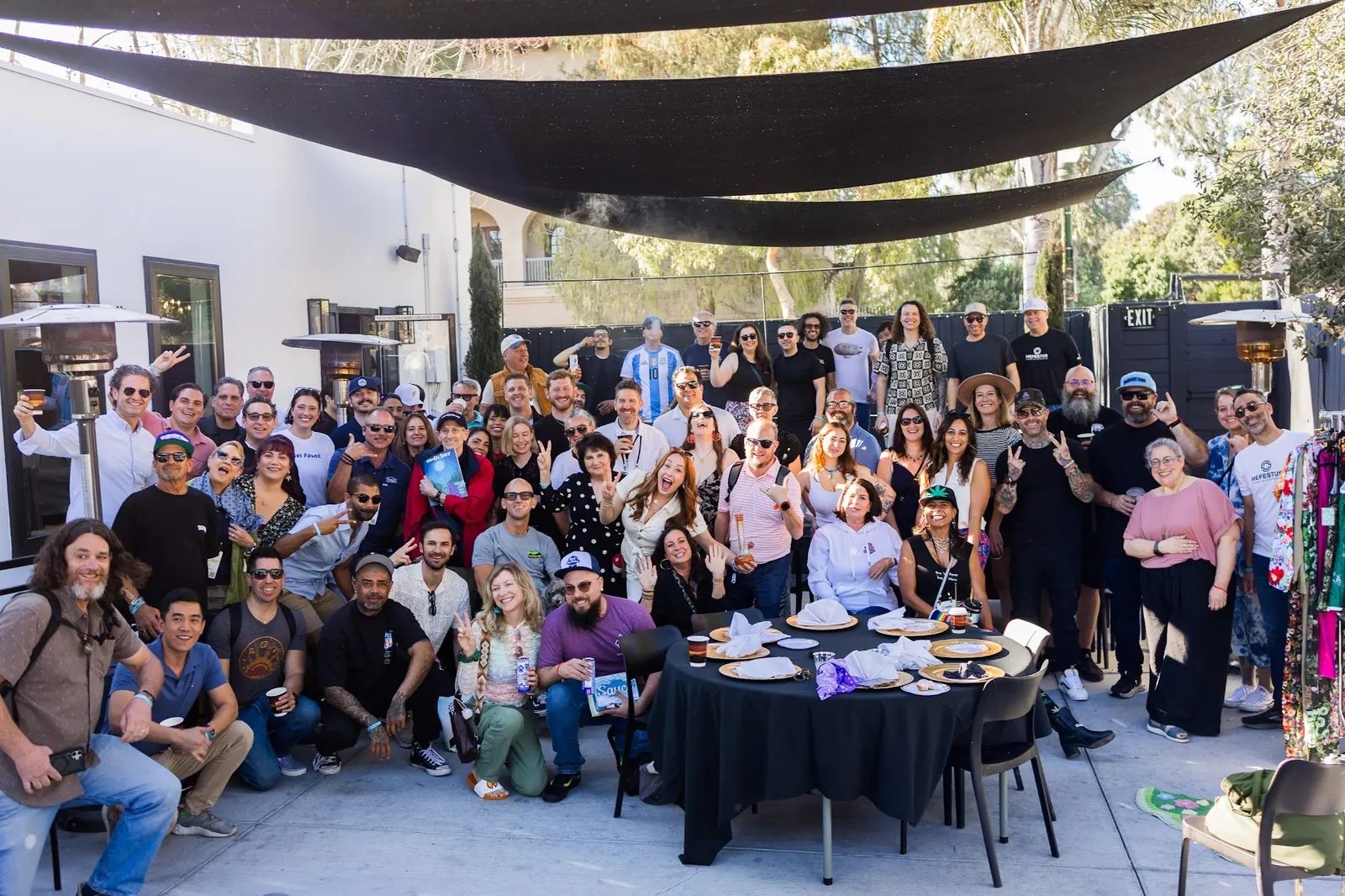 The full group photo from the Bagel Bash at Hall of Flowers, gathered under shade sails at White House Beach Club
